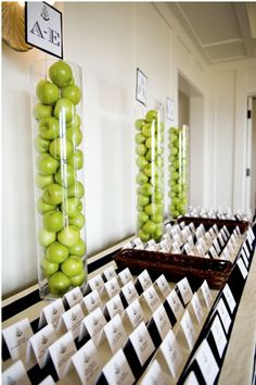 there are many green apples on display in the room with black and white checkered flooring