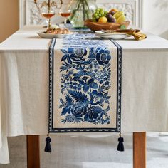 a blue and white table runner with tassels on it, sitting at a dining room table