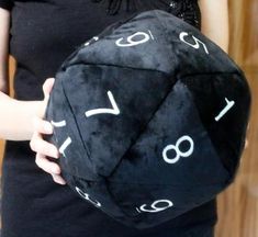 a person holding a black dice with numbers on it