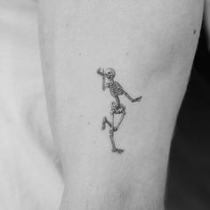 a small skeleton tattoo on the left inner arm and lower arm, with an outline of a running man