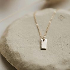 She may be tiny, but she is mighty! We love the versatility of this tiny tag necklace. It’s beautifully hammered edges give her just enough pop and personality. Wear it alone or pair it with multiple chains for a layered look. * tiny 5mm x 10mm rectangle tag. * we hammer just the edges for a subtle detail. * suspended from 16" of our daintiest isla chain. * available in 14kt gold fill + sterling silver. * handmade in Eau Claire, WI. All of our jewelry is handmade to order just for you so each pi Dainty Everyday Necklace With Rectangular Pendant, Dainty Charm Necklace With Rectangular Pendant, Sterling Silver Rectangular Charm Necklaces For Everyday, Minimalist Everyday Dog Tag Charm Necklaces, Everyday Charm Necklace With Delicate Rectangular Pendant, Minimalist Dog Tag Necklace For Everyday, Everyday Minimalist Hammered Charm Necklaces, Dainty Rectangular Pendant Bar Necklace For Everyday, Minimalist Hammered Jewelry With Rectangular Pendant