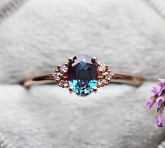 an engagement ring with a blue stone surrounded by purple flowers