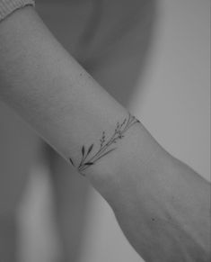 a woman's arm with a small flower tattoo on the left side of her wrist