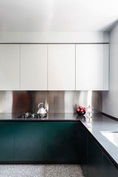 a kitchen with stainless steel cabinets and green counter tops, along with a bowl of fruit on the counter