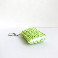 a green crocheted book keychain on a white surface