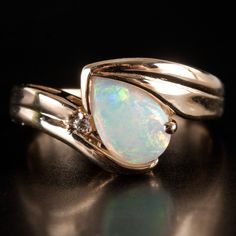 an opal and diamond ring on a black surface