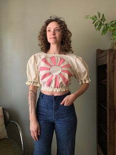 "* Manitou Handmade * Dresden Plate appliqué crop blouse with puff sleeves and elastic waist. * Shoulders 15.5\" Chest 35\" Length 16.5\" Waist 24\" to 31\" PLEASE READ! *MEASUREMENTS* All items are measured while laying flat and unstretched. For clothing: chest, waist, hip and thigh measurements should be multiplied by two. All measurements are in inches. *VINTAGE CONDITION* Vintage goods may show signs of wear and age. We always indicate and/or show in pictures any major flaws or blemishes, but will not always mention small flaws, such as pinpoint sized spots or holes. If you are concerned about a particular item's condition, please message us. All of our pieces are pre-owned. We use a natural detergent to wash all our textiles when necessary (with a few exceptions such as rugs/nail apro Summer Puff Sleeve Top With Patchwork, Fitted Crop Top With Elastic Sleeves, Fitted Cropped Crop Top With Elastic Sleeves, Spring Puff Sleeve Top With Elastic Waistband, Summer Puff Sleeve Crop Top With Elastic Sleeves, Spring Cropped Elastic Sleeves Crop Top, Spring Cropped Crop Top With Elastic Sleeves, Cotton Crop Top With Elastic Waistband, Summer Cropped Puff Sleeve Top With Blouson Sleeves