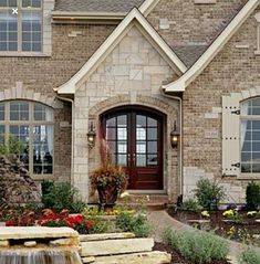 a large brick house with a waterfall in the front yard and landscaping around it's entrance