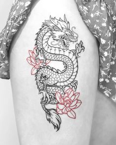 a woman's thigh with a dragon tattoo on the side and flowers around it