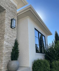 a white house with a large window and planter on the front steps next to it