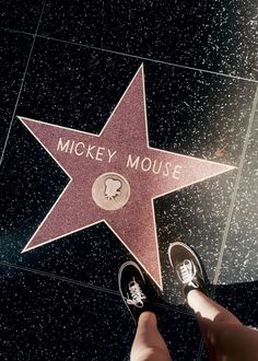 a person standing next to a star on the hollywood walk of fame with their feet up