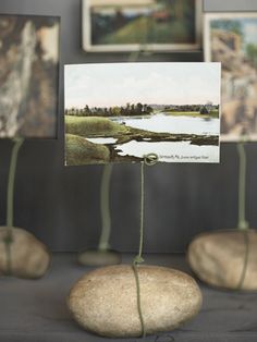 there are some pictures on the table with rocks in front of them and one is holding a piece of art