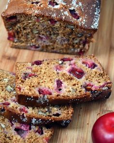 sliced loaf of fruit bread on a cutting board next to an apple