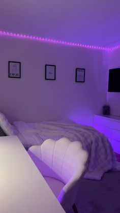 a bed room with a neatly made bed and purple lights on the wall above it