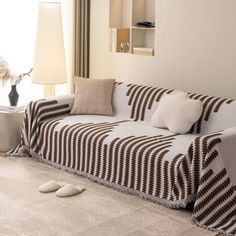 a living room with a couch, lamp and rugs on the floor in front of a window