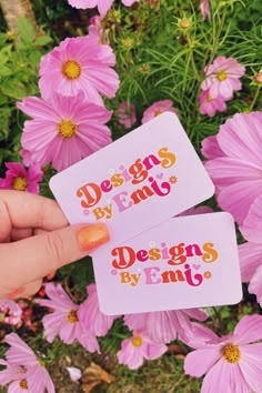 someone is holding two business cards in front of some pink flowers with the words designs by emy on them