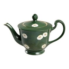 a green tea pot with white flowers on it