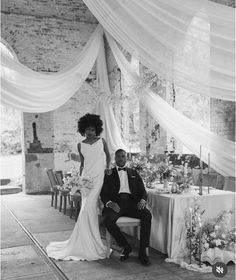 a bride and groom pose for a photo in front of the table set up at their wedding reception