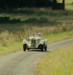 an antique car driving down a country road