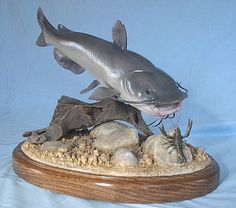 a statue of a fish on top of some rocks and sand with a spider crawling in it