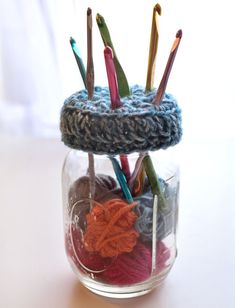 a jar filled with yarn and knitting needles