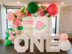 a one in a melon themed birthday party with balloons and watermelon decorations