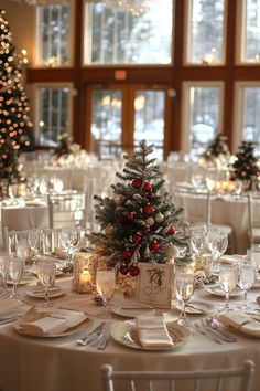 a christmas tree sits on top of a table with place settings and wine glasses in front of it