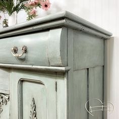 an old dresser with flowers in the background