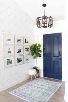 an entryway with blue doors and pictures on the wall, rug in front of it