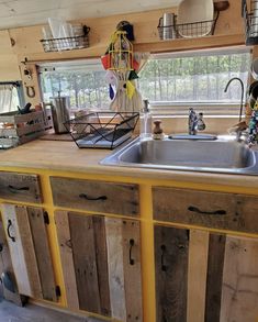 a kitchen area with sink, cabinets and baskets on the counter top in front of a window