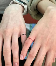 two people with rings on their fingers and one has a small cross on the middle finger