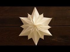 a white origami star hanging on a wooden wall