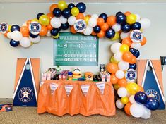 an orange, white and blue balloon arch over a table filled with snacks on it