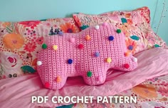 a pink crocheted elephant pillow sitting on top of a bed