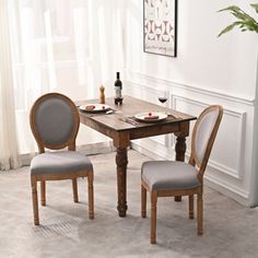 a dining room table with two chairs and a wine bottle on the table next to it