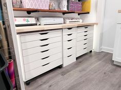 an organized closet with white drawers and lots of crafting supplies on the counter top