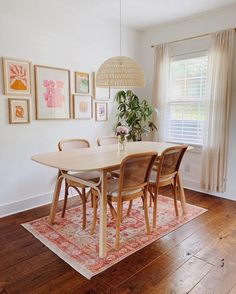 a dining room table and chairs with pictures on the wall behind it in front of a window