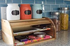 three jars sitting on top of a wooden shelf next to a blue tile backsplash