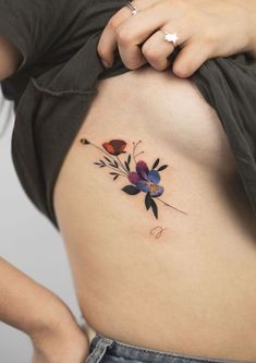 a woman's stomach with a flower tattoo on her lower side ribcage