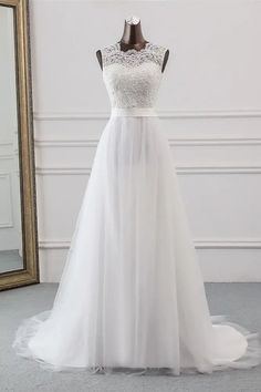 a white wedding dress on a mannequin with a mirror in the corner behind it