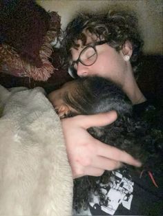 a man sleeping with his head on a woman's shoulder while she is wearing glasses