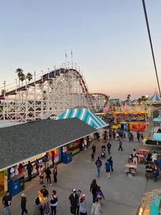 people walking around an amusement park at sunset