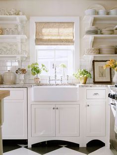 a white kitchen with black and white checkered flooring, open shelving above the sink