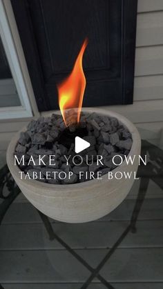 a bowl filled with rocks sitting on top of a table next to a fire pit