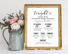 a wedding seating chart with pink flowers in a silver vase next to a gold frame