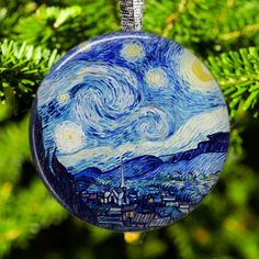 a glass ornament hanging from a tree with a starry night sky painted on it