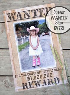 an old photo frame with the words wanted and a cowboy hat on it, sitting next to some grass