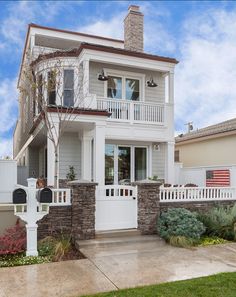 a white two story house with an american flag on the front door and fence around it