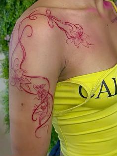 a woman with a tattoo on her arm and shoulder is looking at the camera while wearing a yellow tank top