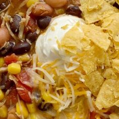 a bowl filled with beans, corn and tortilla chips topped with sour cream